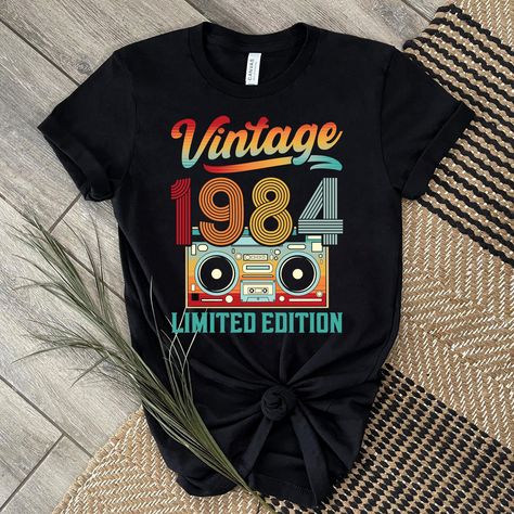 Step back in time with our vintage 1984 shirt, a classic piece that celebrates the retro vibe of the 80s. This single-stitch tee is perfect for commemorating a 40th birthday or as a unique gift for someone born in 1984. With its nostalgic cassette design and retro style, our 1984 shirt is a must-have for anyone looking to add a touch of old-school cool to their wardrobe. Make a statement and stand out from the crowd with this timeless and stylish piece that pays homage to the year 1984 in a fun and fashionable way. Vintage 1Vintage 1984 Shirt, Vintage 1984 Shirt, Classic 1984 Shirt, 1984 Retro Shirt, 1984 Birthday Shirt, Single Stitch, 40Th Birthday Shirt, 1984 Gift Tee, 40Th Birthday Gift, 1984 Cassette Shirt, Retro Birthday Tee, Born In 1984 Tee, 1984 Retro Shirt984 Shirt | 40Th Birthday 1984 Birthday, Cassette Design, 1984 Shirt, 40th Birthday Shirts, 40th Birthday Party, Retro Birthday, 40th Birthday Parties, Birthday Tee, 40th Birthday Gifts