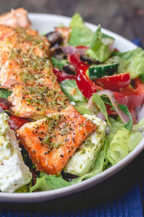 You'll love this easy, wholesome salmon salad! Baked salmon with a Greek-style salad, loaded with crispy fresh vegetables, feta and olives. Wait till you taste the lemon-mint vinaigrette that pulls everything together! You'll love it. #salmonsalad #salmon #fish #greeksalad #greekfood #mediterraneandiet #mediterraneanfood #mediterraneanrecipes #fishdinner #saladbowls Mediterranean Salads, Seafood Salads, Grilled Salmon Salad, Traditional Greek Salad, Salmon Salad Recipes, The Mediterranean Dish, Yummy Salads, Resep Salad, Greek Flavors