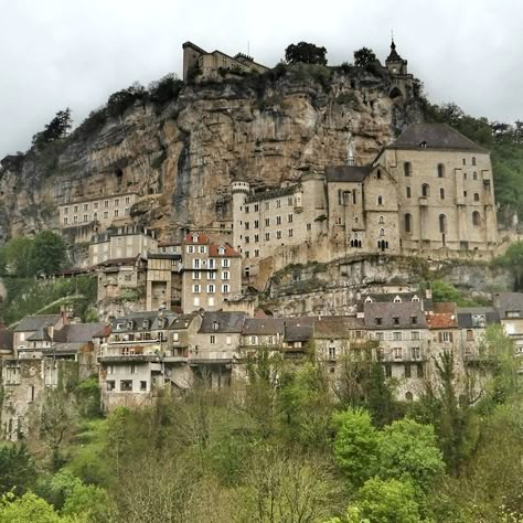 the medieval village of rocamadour, a sacred town perched on the side of a limestone cliff. val du lot. occitanie. france Medieval Mountain Village, Mountain Side Village Minecraft, Cliff Side Castle, Minecraft Cliff Village, Mountain Side Village, Rocamadour France, Story References, Fantasy Journal, Medieval Fair