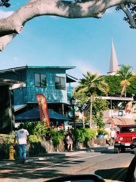 Driving down a small road in Hawaii. There’s a bright blue building on the left with a rainbow going over. A red jeep going down the street. Kona Hawaii Aesthetic, Hawaii Neighborhood, Beach Town Aesthetic, Kona Beaches, Kailua Kona Hawaii, Living In Hawaii, Town Aesthetic, Kona Hawaii, Hawaii Homes