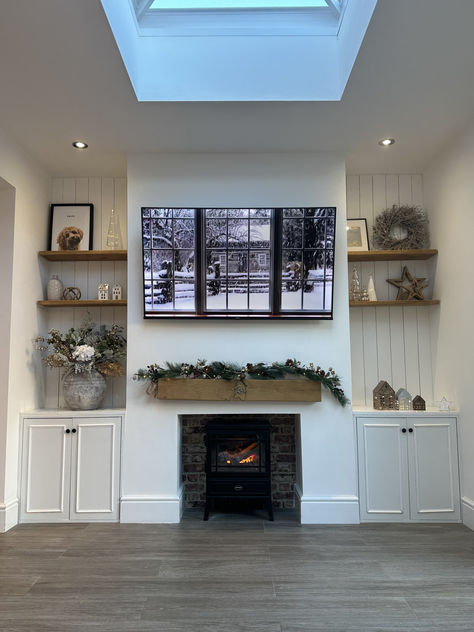 A TV with a winter scene sits on top of a fireplace. To the left and right, shelves contain metcallic decorations. Brick Fireplace Log Burner, Log Fire, Fireplace Logs, Decor Fireplace, Log Fires, Living Room Decor Fireplace, Christmas Interiors, Log Burner, Christmas Fireplace