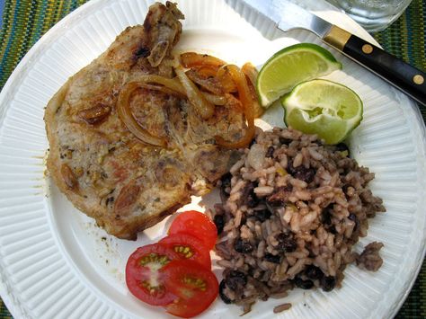 Cuban pork chops with a side of beans and rice, garnished with fresh tomato and lime wedges Cuban Pork, Travel To Cuba, Recetas Puertorriqueñas, Cuban Dishes, Latin American Recipes, Cuban Cuisine, Cuban Style, Latin Recipes, Cuban Food