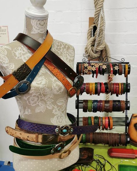 This is a good example because it shows a variety of different styles and colors of belts, as well as a variety of different bracelets that coordinate. This display is also effective because it shows the belts clasped and on a mannequin. Belts are rarely displayed this way and seeing the belt clasped makes it much easier to see how it’s going to look on someone’s body. The floral pattern and neutral colors of the display, along with the rope and iron accents add to the aesthetic of the display. Belt Display Retail, Vintage Clothing Display, Craft Fair Booth Display Ideas, Fair Booth Display Ideas, Leather Cord Holder, Vendor Booth Display Ideas, Leather Cord Organizer, Fur Projects, Table Booth