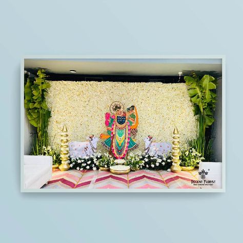 We wanted to let you know that we recently designed a beautiful flower pasting backdrop of Shree Nath ji. We used high-quality Ramban and Rajnigandha flowers for the arrangements, and for the spiritual backdrop, we used white Desi flowers with a brass prop. The overall effect was stunning and created a serene atmosphere. We would love to discuss more with you about our flower arrangement services and how we can help create a beautiful and meaningful atmosphere for your next event. Krishna Backdrop Decoration, Mayra Decoration, Krishna Decoration Ideas, Desi Flowers, Pichwai Designs, Leaf Decor Wedding, Wedding Walkway, Puja Ghar, Indoor Wedding Decorations