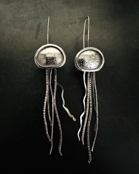 Do you love the beauty of sea creatures? Dive into the beautiful world of undersea creatures with these sterling silver jellyfish earrings. Crafted with meticulous detail, each delicate tentacle dances gracefully, capturing the fluid movement of these majestic creatures. The patina adds a touch of depth and character, reminiscent of the ocean’s mysteries. Embrace the beauty of the sea. #silverjellyfish #elegantearrings #oceaninspired #patinaperfection #undertheseastyle #ooakjewelry #sterl... Jellyfish Earring, Undersea Creatures, Jellyfish Earrings, Fluid Movement, Majestic Creatures, Fish Jewelry, Ocean Inspiration, Elegant Earrings, Jellyfish