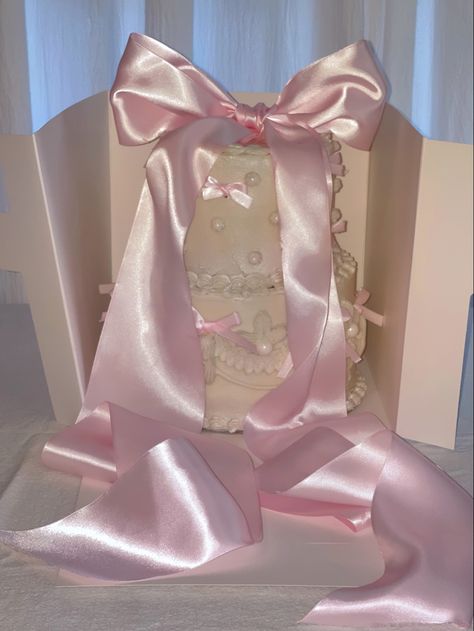 two tier cake with vintage piping, pearlescent glaze, edible pearls, and a mix of small and large pink ribbons Pink Bow Cake, Baby Pink Bow, Bow Cake, Ribbon Cake, Pearl Cake, Edible Pearls, Two Tier Cake, Girly Cakes, Bow Cakes