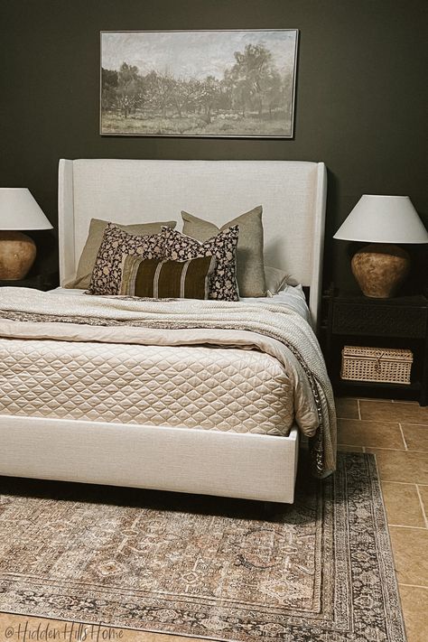 Master bedroom with dark and moody walls with a cream upholstered bed, dark wood nightstands, and olive tones throughout! Cream Bed Frame Room Ideas, Dark Upholstered Bed, Dark Green Accent Wall, Cream Upholstered Bed, Beige And Black Bedroom, Beige Bed Frame, Tilly Upholstered Bed, Olive Bedroom, Neutral Throw Pillow