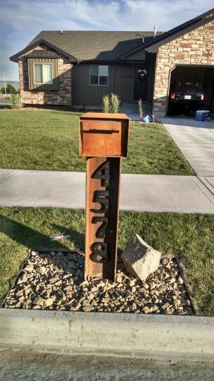 Steel mailbox adds rustic flare to curb appeal of this house exterior. Steel Mailbox Ideas, Mid Century Mailbox, Entry Patio, Rustic Mailboxes, Mailbox Stand, Log Cabin Exterior, Mailbox Makeover, Low Maintenance Yard, Ranch Gates