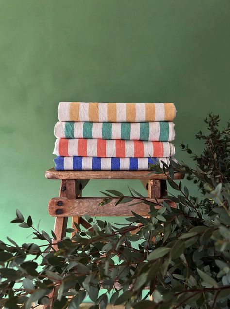 Welcome Bohemia 🌍   Sorrento Hammam Towels in mustard, olive, orange, indigo; a classic stripe cotton towel reminiscent of childhood beach holidays and jaunty sunshades. Produced by a family of weavers in Turkey using locally harvested cotton.  Collaborating with artisans from Morocco to Turkey, Bohemia brings timeless, functional objects with a contemporary twist. Celebrate authentic craftsmanship and sustainable production. 🌺⁠  Follow the link to shop the collection! Resort Aesthetic, Bohemia Design, Nautical Colors, Beach Basket, Linen Tableware, Green Towels, Hammam Towels, Mens Holiday, Peshtemal Towel