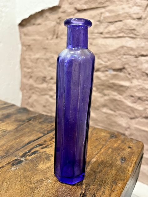 Elevate your home decor with this exquisite 7" single stem vase, featuring a striking purple hue that adds a touch of elegance to any space. The vase is meticulously crafted from high-quality glass, showcasing a glossy finish that enhances its classic beauty. Its unique eight-sided design provides a distinctive flair, making it a standout piece for your collection or as a centerpiece in your living or dining area. Whether displaying fresh blooms or standing alone as a decorative piece, this vintage-inspired vase brings a timeless charm to your interior design. Its versatile color and sophisticated silhouette make it an ideal complement to a variety of decor styles, from contemporary to traditional settings. Add a splash of color and grace to your home with this beautiful glass vase. Single Stem Vase, Vintage Bottle, Purple Glass, Classic Beauty, Splash Of Color, Dining Area, Glass Vase, Decor Styles, Vintage Inspired