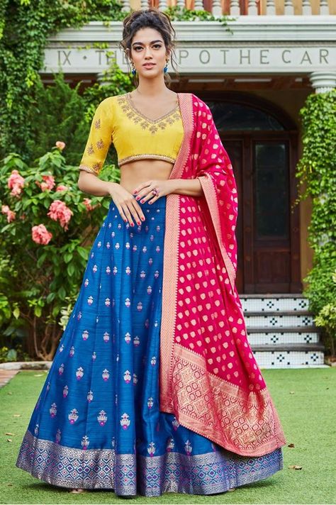 Leave the crowd spellbound wearing this spectacular designer lehenga choli set featuring a blue lehenga done up all over in zari & weave motifs followed by same work border while the choli stands out in yellow worked along the neckline & sleeves in zari & gota motifs and work in a telltale finish! This lehenga choli set is accompanied with contrasting pink dupatta. Lehenga Color Combinations, Lehenga Bridesmaid, Bridal Lehenga Online, Designer Bridal Lehenga Choli, Pink Dupatta, Bridesmaid Lehenga, Yellow Lehenga, Lehenga Designs Simple, Designer Bridal Lehenga