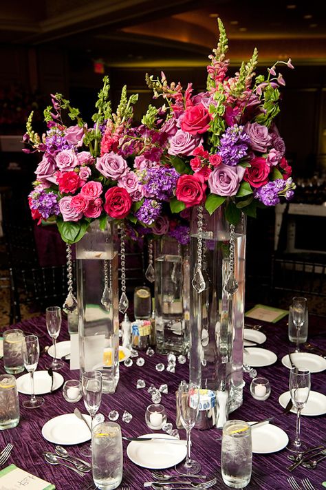 table setting at reception - three tall glass vases with danging crystals with dark pink, light pink, purple, and green floral arrangements as centerpiece and purple tablecloth - photo by Houston based wedding photographer Adam Nyholt Wedding Table Settings Purple, Wedding Planning Gifts, Pink Table Settings, Wedding Reception Tablescapes, Purple Tablecloth, Purple Centerpieces, Tall Glass Vases, Trendy Wedding Favors, Pink Centerpieces