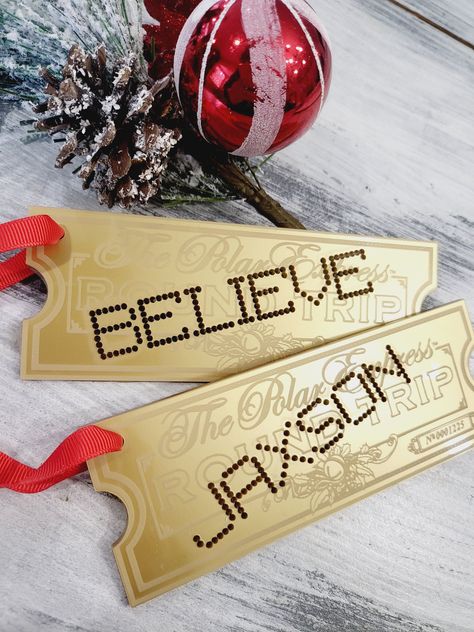 "We are so excited to share these new personalized ornaments with you! Polar express ornament personalized train ticket Christmas ornament polar express train ticket gold believe magic acrylic ornament We engrave gold acrylic ornament with your choice  and punch out the personalized name or word of your choosing they are then hung red ribbon to easily add to your tree or Christmas stocking. Choose from either \"BELIEVE\" or your Childs name to be cut out as if it were hole punched! Tags ornaments are 6inches x 2.5 inches to provide a perfect size ornament or stocking tag.  These ornaments are sure to add to your Christmas magic this year and for years to come. please note the back of these are black due to the fact they are made from mirror acrylic" The Polar Express Christmas Decorations, Diy Train Ornaments, Diy Polar Express Ticket, Polar Express Golden Ticket Printable, Polar Express Themed Christmas Tree, Polar Express Theme Christmas Tree, Polar Express Decorations Diy, Polar Express Christmas Tree Theme, Polar Express Christmas Decor