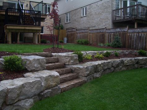 Backyard multi-level stone wall and flowerbeds feature Backyard Retaining Walls, Stone Walls Garden, Terraced Backyard, Stone Wall Design, Backyard Garden Layout, Stone Landscaping, Sloped Backyard, Stone Retaining Wall, Landscaping Retaining Walls