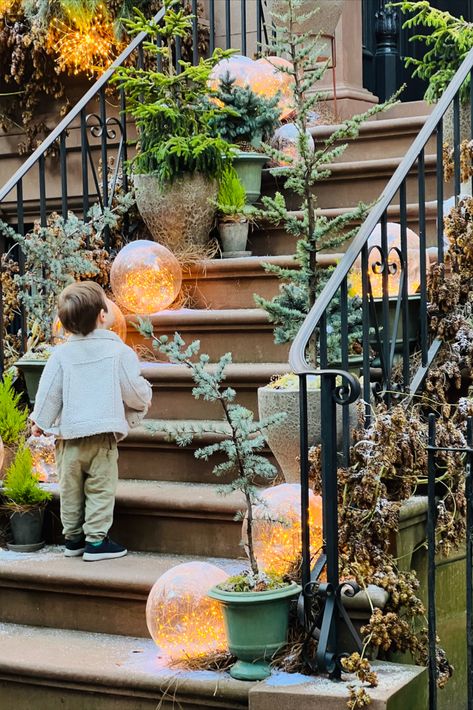 front stoop decorated for the holidays with lights and trees, wreaths Brownstone Christmas, Anthropologie Christmas Decor, Winter Front Porch, Anthropologie Christmas, Anthropologie Holiday, Brooklyn Brownstone, Window Candles, Kitsch Christmas, Magical Home