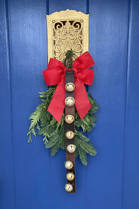 Jingle bells on a leather strap. Bells are attached to the strap with a leather lace. Hanging on a blue and gold door over an evergreen arrangement with a red bow. Decorate With Sleigh Bells, Sleigh Bells On Leather Strap, Decorating With Sleigh Bells, Christmas Bells Craft, Diy Sleigh, Homemade Door, Craft For Christmas, Craft For Adults, Winter Holiday Decorations