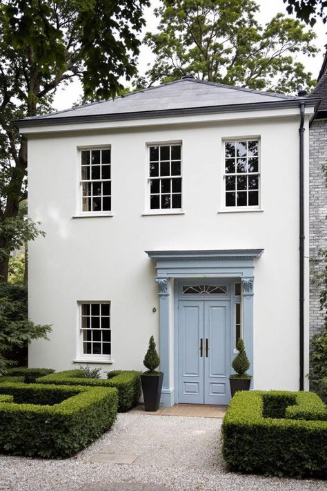 White Georgian house with blue door and manicured hedges. Ready to prance through history with a dash of charm? This design collection will fill you in on Georgian homes, where symmetry, elegance, and a hint of aristocratic flair meet delightful practicality. White Georgian House, House With Blue Door, Georgian Houses, Roof Cap, Black Shutters, Elegant Doors, Blue Shutters, Georgian House, Georgian Architecture