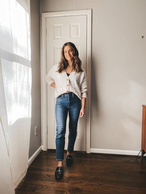 ashley wearing a cream colored button front cardigan buttoned up with a black bodysuit underneath, mid-wash straight leg jeans, and black loafers, standing in front of a white door with a window and sheer white curtain to the side Buttoned Cardigan Outfit, Button Down Cardigan Outfit, Layering Fall Outfits, Cardigan Jeans Outfit, Button Cardigan Outfit, Ways To Style A Cardigan, Cream Cardigan Outfit, Layered Clothes, Layering Dresses