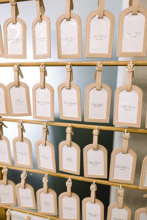 Wedding seating chart made of personalized luggage tags Luggage Tag Display, Travel Tag Seating Chart, Seating Chart Individual Cards, Wedding Seating Chart With Gift, Name Tag Wedding Table Seating Charts, Wedding Seating Board Ideas, Luggage Tag Place Cards, Seating Chart Favors, Seating Chart Wedding Favors