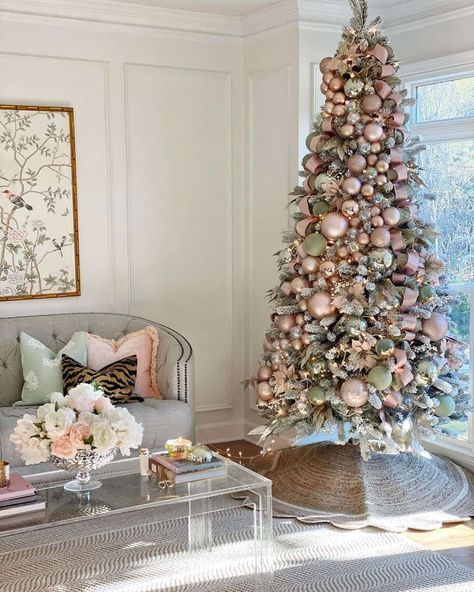 A tufted gray living room sofa is accentuated by a colorful arrangement of accent pillows. Pink, green, and gold decorations adorn a tree that displays Christmas tree skirt ideas. The jute tree skirt surrounds the tree base overlapping a patterned gray rug...   Image: littlelattihouse Jute Tree, Full Christmas Tree, Flocked Trees, Warm White Led Lights, Creative Christmas Trees, Minimalist Apartment, Flocked Christmas Trees, Candy Christmas, Pink Christmas Tree