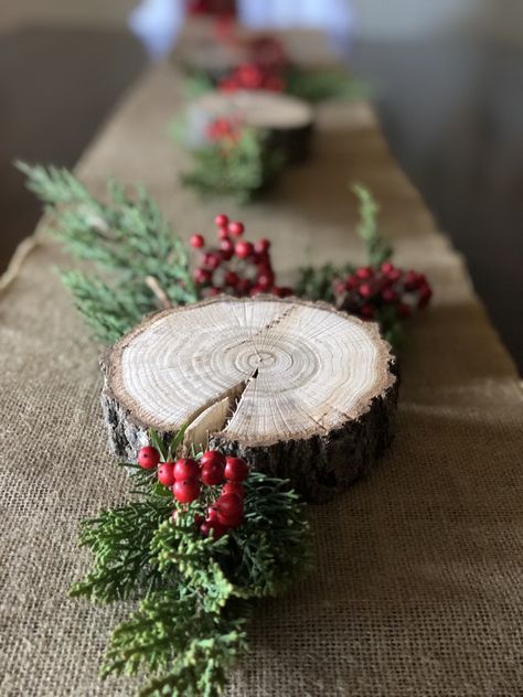 Wood slices with evergreen trimmings make the perfect simple holiday touch to your holiday table setting. Wood Slices Table Decor, Simple Rustic Christmas Table Decor, Wood Centerpieces Christmas, Wood Slice Christmas Centerpiece, Rustic Christmas Party Decor, Christmas Banquet Round Table Decorations, Rustic Christmas Table Decor, Ward Christmas Party Table Decorations, Pine Tree Centerpiece Table Decorations