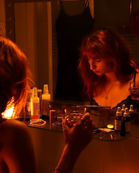 Girl with red hair getting ready in front of a mirror. She is holding a glass of whiskey while doing her makeup. Staged Photography Scene, Cinematic Photography Bathroom, Bathroom Film Photography, Bathroom Getting Ready Aesthetic, Orange Portrait Photography, Bathroom Movie Scenes, Messy Bathroom Aesthetic, Underconsumption Aesthetic, Girl Bathroom Aesthetic