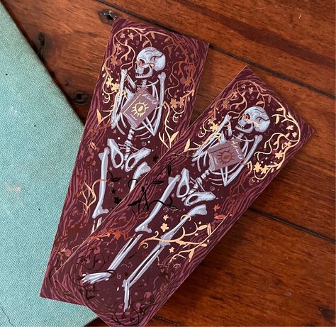 ✨The Librarian ✨Gold foil detailed occult bookmark ✨ This gorgeous bookmark is stylistically inspired by Medieval woodcut and Occult art and was created digitally using a limited colour palette. The design came about after thinking about what items I would take with me to the grave and honestly the first thing I thought of was my favourite books. The design is  inspired by archaeological dig sites with skeletons.  The bookmark is printed onto gorgeous thick 700gsm card, giving it a feeling of sturdiness and luxury. Both sides of the card are foiled in gold and the edges of the bookmark are beautifully gold painted giving this piece a unique feel.  Perfect gift for a book lover or owner of gothic stationary. Or you could treat yourself and buy this to match your own macabre book! Scary Bookmarks, Art Nouveau Bookmark, Gothic Bookmarks, Medieval Woodcut, Goth Bookmark, Spooky Bookmarks, Art Skeleton, The Librarian, Skeleton Skull