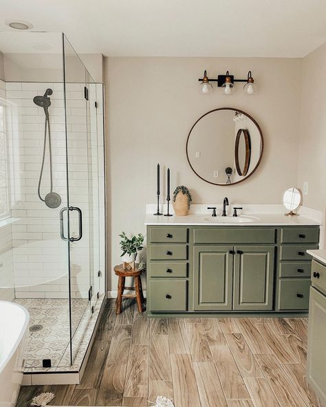 Olive green bathroom vanity with white countertop is paired with a wood frame round bathroom mirror. The vanity stands next to a white staggered tile shower with frameless glass enclosure. Olive Green Bathrooms, Sage Green Bathroom, Black Bathroom Hardware, Green Bathroom Vanity, Bathroom Redecorating, Green Vanity, Bathroom Color, Green Cabinets, Bathroom Inspiration Decor