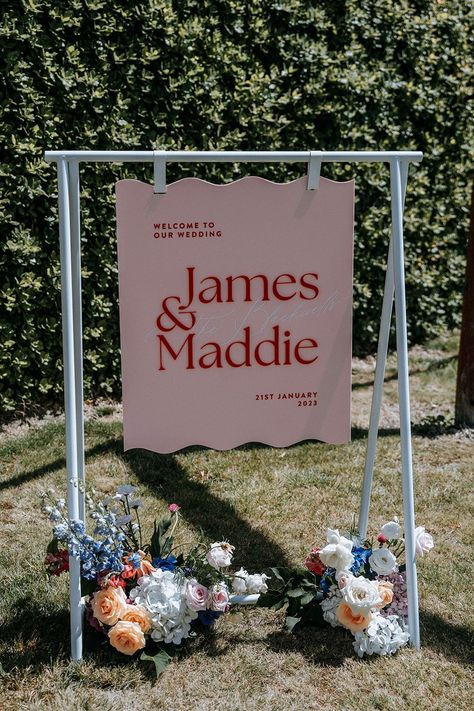 Colourful and luxurious wedding in Martinborough, New Zealand. Beautiful pink acrylic wavy edge wedding welcome sign with bright red acrylic and vinly cut graphics to add depth and a premium look. Complimented by stunning bright wedding florals. Bridgerton Welcome Sign, Wavy Wedding Signage, Wavy Welcome Sign, Colourful Wedding Signage, Acrylic Signs Wedding, Pink Wedding Sign, Acrylic Wedding Signs, Floral Wedding Sign, Welcome Wedding Sign