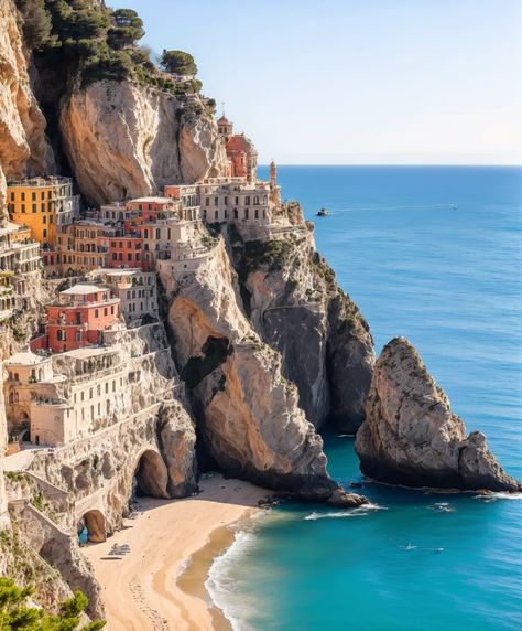 The image shows a beautiful coastal village built on a cliffside. The village is surrounded by sheer cliffs and turquoise blue sea. The houses in the village are built close together and are painted in a variety of colors. The village is accessible by a road that winds its way up the cliffside. There is a small beach at the bottom of the cliff, and a few boats are anchored in the bay. The water is crystal clear and a deep blue color. The sky is blue and there are a few clouds in the House On A Cliff By The Sea, Coastal Village Aesthetic, Coastal City Aesthetic, Cliffside Town, Cliffside Village, Town By The Sea, Cliffside House, Village By The Sea, Novel Aesthetic