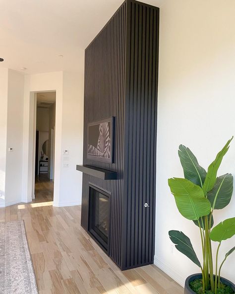 Black Fireplace Mid Century, White Walls With Feature Wall, Black Fluted Fireplace Wall, Black Herringbone Fireplace Surround, Feature Wall Above Fireplace, Black Wood Panel Fireplace Wall, Black Wood Slat Fireplace Wall, Wooden Slat Fireplace, Black Fireplace Vaulted Ceiling