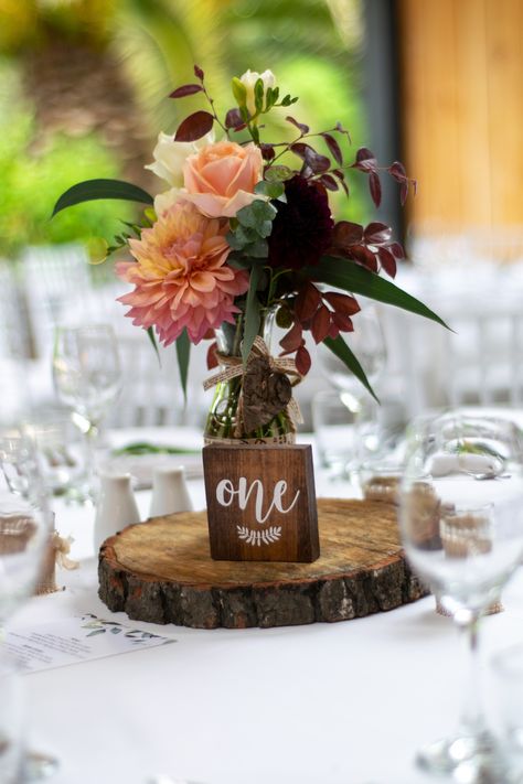 Warm tone flowers in vase on wedding table with log and table one wooden block #wedding #weddinginspiration #weddinginspiration #weddingphotography #centrepiece #weddingtable #weddingtabledecorations #tabledecoration #kumeuvalleyestate #vintagewedding #rusticfeel #farmhousevibe #nzwedding #engaged #married Mill Wedding, Log Slice, Rustic Autumn, Flowers In Vase, Table Centrepiece, Warm Tone, Wedding Table Decorations, Centre Piece, Wildflower Wedding