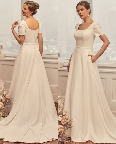 Looking for something simple and elegant? Look no further than Moonlight Modesty M5051! The sleek crepe A-line dress features a chic square neck, square back and short puff sleeves to create a simple yet lovely bridal look. Not to mention the couture waist band and side pockets at skirt! With its lightweight, clean-cut sweep train, M5051 will add the perfect touch of elegant simplicity to your secret garden or whimsical floral wedding. #crepeweddingdress #alineweddingdress #simpleweddingdress Simple Petite Wedding Dress, Short Sleeve Gown, Short Sleeves Wedding Dress, Bridesmaid Dresses Square Neck, Wedding Dress A Line Simple, Dresses With Puffy Sleeves, Simple Bridal Dress, A Line Wedding Dress Square Neckline, Square Neck Line Wedding Dress