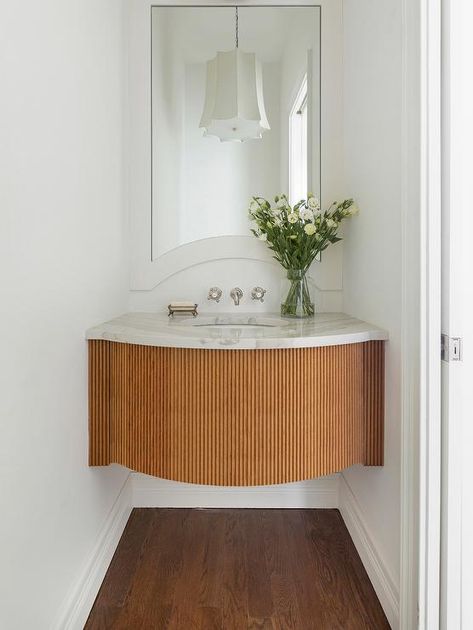 A stunning curved reeded sink vanity is fitted with a marble countertop and fixed beneath a polished nickel cross handle faucet mounted to the wall beneath a curved white framed vanity mirror. Rounded Vanity, Floating Marble Sink, Floating Sink Vanity, Half Bathroom Design, Small Half Bathroom, Bria Hammel Interiors, Miami House, Bria Hammel, Floating Sink