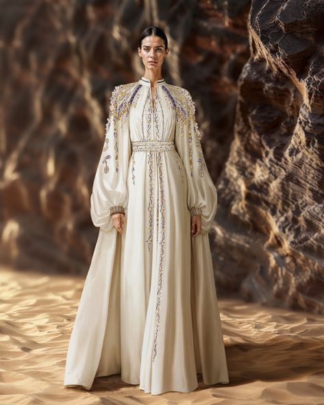 Unveiling the off-white crepe kaftan, paired with a beaded taffeta cape. Embroidery cascades gently from shoulders to skirt, showcasing the impeccable craftsmanship.​ #SaiidKobeisy​​ #Kaftan​ #HauteCouture One Shoulder Cape, Abaya Cape, Cape Outfit, Queen Wedding Dress, Saiid Kobeisy, Kaftan Gown, Bride Headpiece, Pretty Wedding Dresses, Couture Embroidery