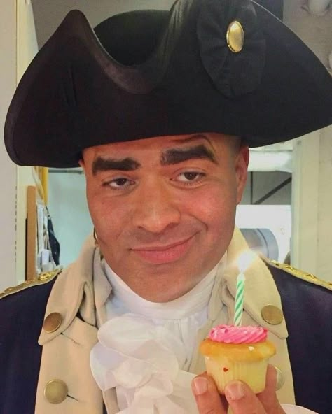 Christopher Jackson dressed as General George Washington (complete with tricorn hat) is smirking while holding in his left hand, a very tiny vanilla cupcake with pink frosting and a small green candle which is lit, the light of which is reflected in the actor’s dark brown eyes. Hamilton George Washington, Lams Hamilton, Cast Of Hamilton, Christopher Jackson, Hamilton Cast, Musicals Funny, Hamilton Jokes, Hamilton Fanart, Hamilton Broadway