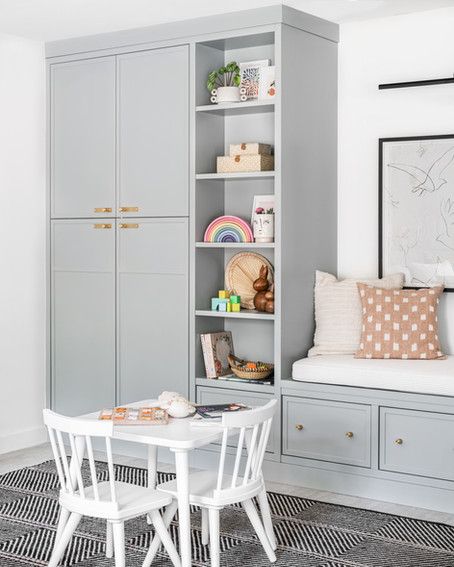 A soft blue green built-in with modern slim shaker-style doors and drawers. The right hand potion of the built in drops into an integrated bench that is finished with a striped cushion. Playroom Built In Storage, Miami Interiors, Miami Interior Design, Home Office Library, Hidden Tv, Miami Houses, Playroom Storage, Residential Interior Design, Toy Rooms