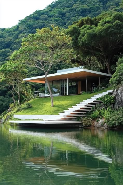 Modern house on a hillside with terraces connected with floating stairs tropical island lake below. Check out all of these stunning lake houses perched on a hill, from rustic charm to modern elegance–all offering breathtaking views. Cliff Homes Architecture, Floating Lake House, Homes Built Into Hillside, Cabin On A Hill, Slope House Design Architecture, Hillside Modern House, Terraced Architecture, Cliff House Architecture, House Built Into Hill