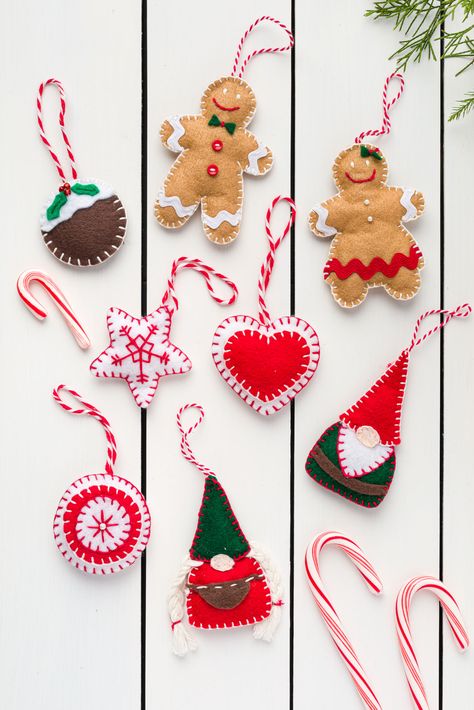 Handmade Felt Christmas Ornaments on a wood table Easy Felt Christmas Ornaments, Christmas Felt Crafts, Diy Felt Ornaments, Diy Felt Christmas, Felt Ornaments Diy, Felt Christmas Tree Decorations, Diy Felt Christmas Ornaments, Christmas Signs Diy, Felt Ornaments Patterns