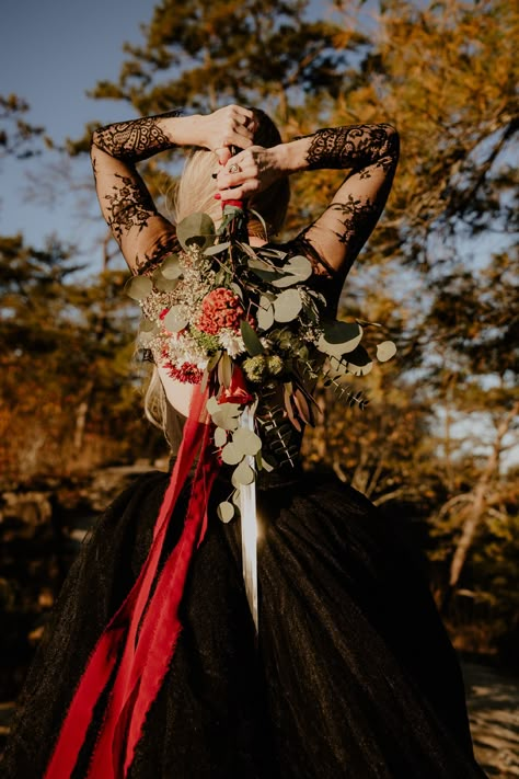 Woman with long blond hair wearing black lace wedding dress holding sword bouquet at Red River Gorge Black Red And Green Wedding, Witch Aesthetic Wedding, Red Black Wedding Theme, Fancy Proposal, Renfaire Wedding, Dnd Wedding Ideas, D&d Wedding, Viking Wedding Ideas, Wedding Swords