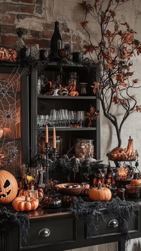 Create a bewitching brew of style with Halloween kitchen decor that casts a spell. Arrange black candles in vintage candelabras on the countertop and display potion recipe cards in antique frames. Hang a collection of rustic wooden spoons painted with Halloween motifs. Place a large, decorative cauldron filled with gourds and pumpkins in a corner. These enchanting Halloween kitchen decor ideas transform your cooking area into a charming witch's cottage, perfect for conjuring up seasonal treats a Witchy Kitchen Halloween, Haunted Kitchen Halloween Decorations, Witches Cottage Halloween Decor, Witches Den Halloween Decor, Halloween Witch Kitchen Decor, Witch’s Lair Decor, Haunted House Dining Room, Kitchen Witch Decor, Witches Cottage