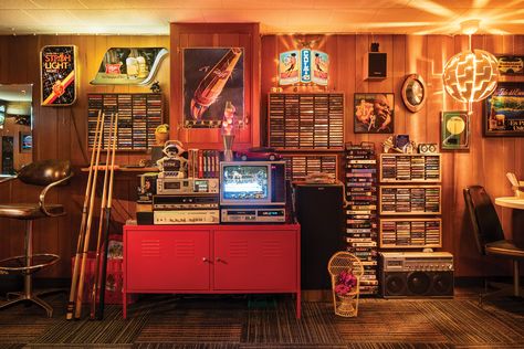 Every corner of this retro rec room exudes a youthful nostalgia, from the kitschy vintage decor to the seemingly endless collection of VHS and cassette tapes on display.

Visit the link below to see more from this nostalgic basement bar.

📸: Ben Clasen Basement Dive Bar, Midwest Home, Chrome Bar Stools, Recreation Room, Vhs Cassette, Building Remodeling, Retro Room, Dive Bar, Blast From The Past