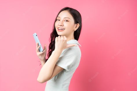 Premium Photo | Young asian woman holding phone in hand and pointing back on pink Girl Holding Phone, Woman Holding Phone, Holding Phone, Pointing Hand, Premium Photo, Casual Women, Casual Wear, Stock Photos, Pink