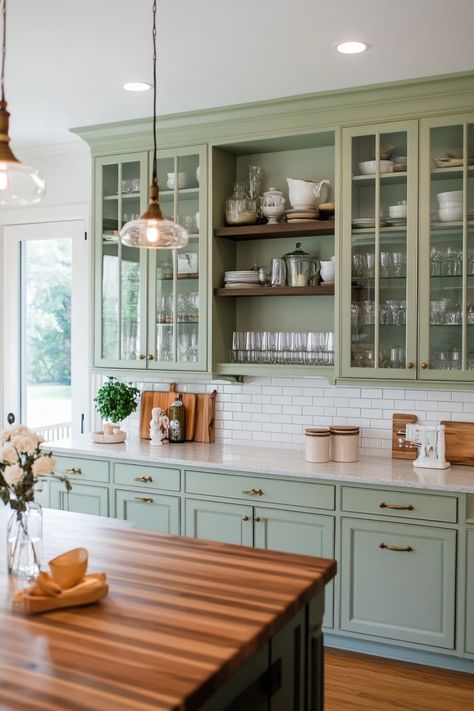 Modern kitchen with sage green cabinets, glass doors, and a wooden island countertop. Devol Kitchens Green, Painted Cottage Cabinets, Cottagecore Kitchen Remodel, Century Home Kitchen, English Kitchen Design, English Kitchens Design, French Provincial Kitchen, French Inspired Kitchen, French Style Kitchen