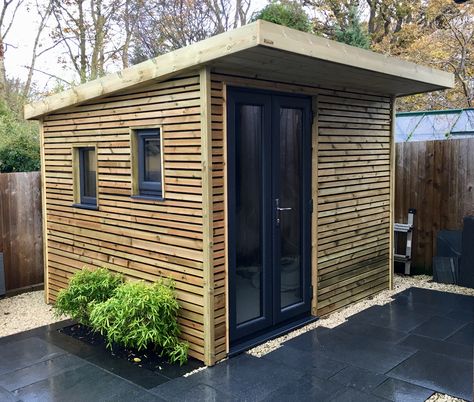 A Bluum shed / garden room - clad with strips of treated timber, painted underneath with ‘blackbird’ garden paint, and fitted with anthracite French doors and windows Shed With Green Roof, Green Roof Tiny House, Green Shed Roof, Wooden Garden House, Dark Green Garden Shed, Green Roof Project, Contemporary Sheds, Oak Framed Garden Annexe, Living Green Roof