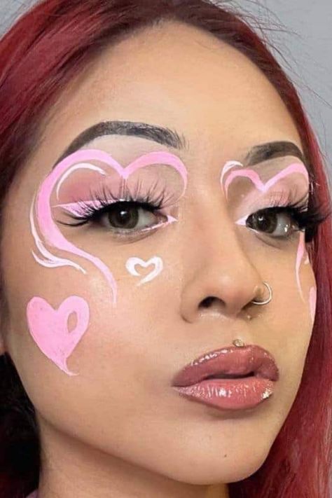 Best valentines makeup looks 2024 Pink Graphic Makeup Looks, Valentine’s Day Graphic Liner, Love Heart Makeup, Pink Graphic Liner Makeup, Pink Face Paint Ideas, Valentines Graphic Liner, Cute Face Painting Aesthetic, Valentines Eyeliner, Pink Graphic Eyeliner