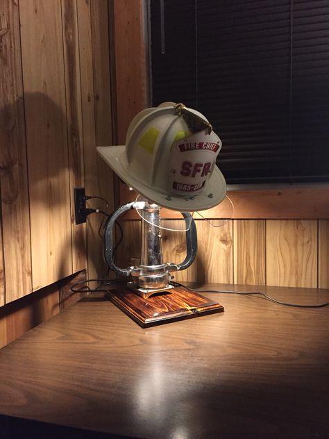 Fire helmet display with lamp Firefighter Display Ideas, Firefighter Helmet Display, Fire Chief Office Ideas, Diy Firefighter Decor, Firefighter Room Man Caves, Fire Helmet Display, Chin Length Layered Hair, Fire Hose Projects, Fire Hose Crafts