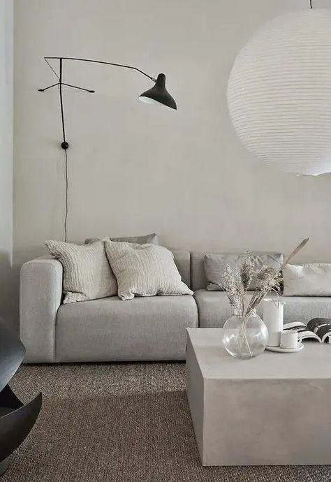 a minimalist greige living room with a grey sofa, a greige stone coffee table, a black sconce and a pendant lamp is amazing Greige Living Room, Black Sconces, Stone Coffee Table, Neutral Living Room, Gray Sofa, Beautiful Living Rooms, Living Room Inspo, A Living Room, Minimalist Interior