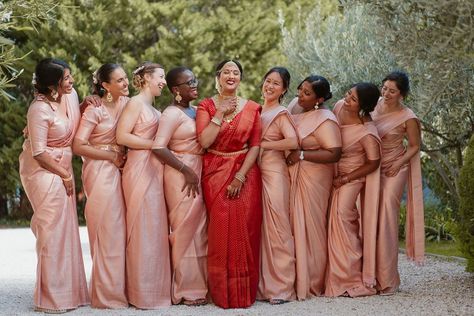 Bridal party with bride in a red lehenga and pink bridesmaids dresses Red Saree Bride With Bridesmaid, Indian Bridesmaids Saree Outfits, Sari Bridesmaid Dress, Telugu Bridesmaids Outfits, Pink Bridesmaid Saree, Indian Bridesmaid Gifts, Bridesmaid In Saree, Tamil Wedding Bridesmaid, Tamil Bridesmaid