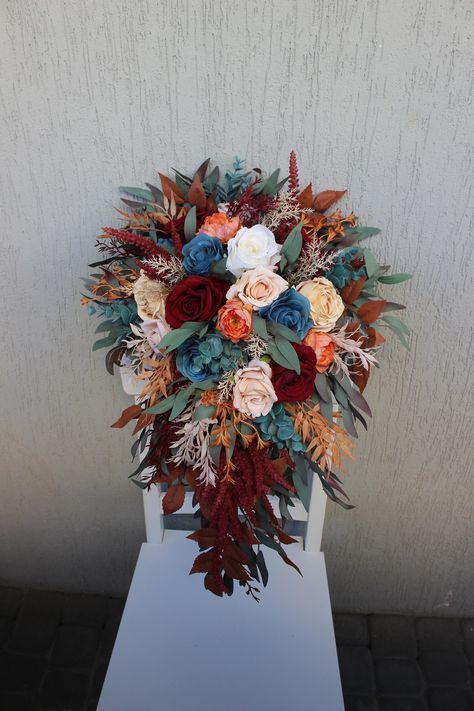 Embrace the rustic charm of autumn with rust fall bridal bouquet, a cascading masterpiece in serene light blue, ivory hues, rich burgundy tones and crafted from lifelike faux and silk flowers, is the epitome of timeless elegance. Perfect for your fall wedding, it adds a touch of nature-inspired romance to your special day. ○ Color: blue, dusty green, red, orange, burgundy ○ Personalization: I can make changes to your wishes ○ Processing time: 1 - 2 weeks ○ Shipping time: 7 - 14 business days NOTE  ○ I ship with REGISTERED mail and you will get a tracking number.  ○ All items will be carefully packed in special package materials.  ○ The actual color may differ slightly from the one you see on your monitor screen, as it depends on the specific monitor settings.  ○ In case some materials are Burgundy And Teal Wedding, Dark Teal And Burnt Orange Wedding, Teal And Burgundy Wedding, Wedding Bouquets Fall, Fall Theme Wedding, Wedding Bouquet Cascading, Burgundy Wedding Bouquet, Bouquet Fall Wedding, Fall Bridal Bouquet